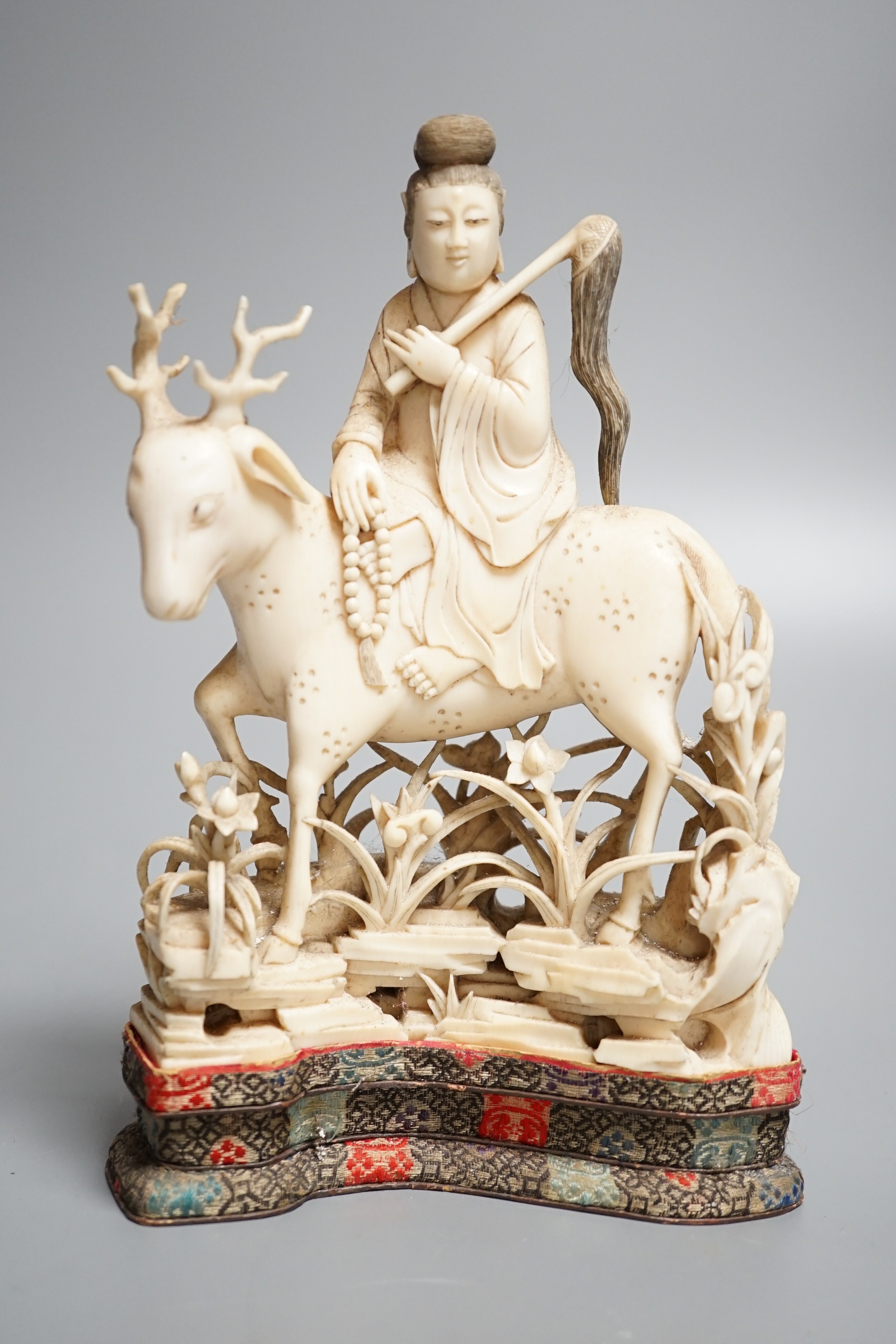 A Chinese carved ivory figure of a female immortal riding a deer, early 20th century, height 17cm excl. stand